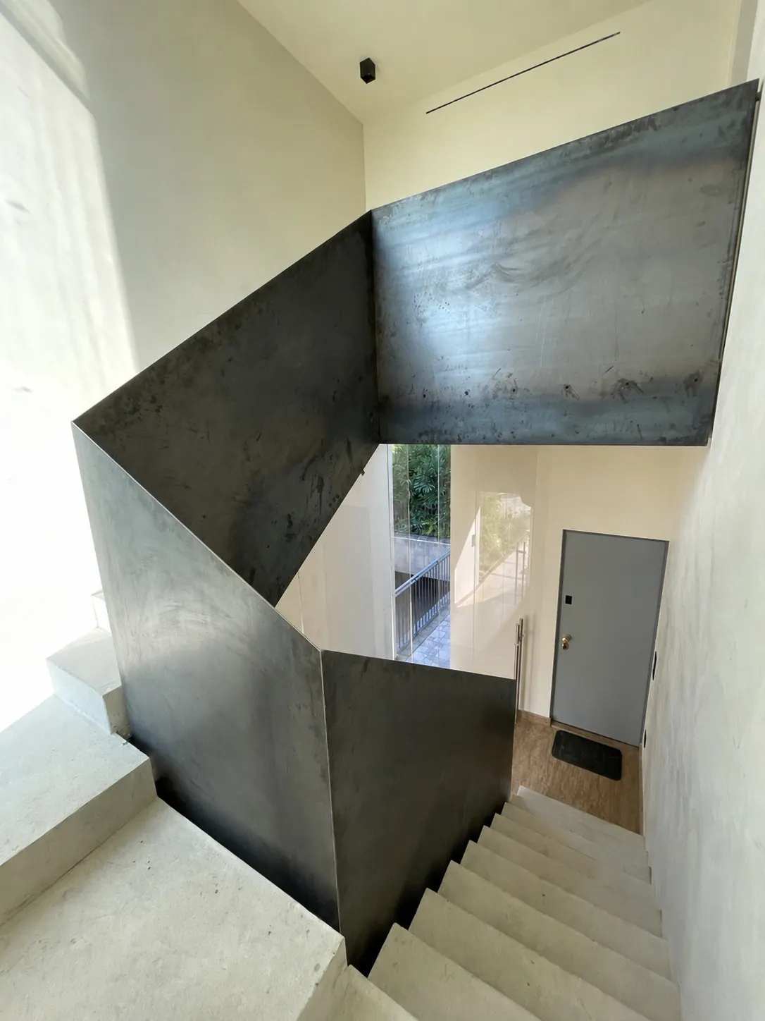 Scala interna con parapetto in lamiera d'acciaio brunito tra pareti chiare