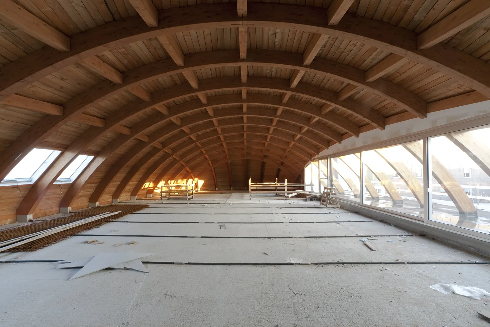 Il piano sotto la copertura lignea durante il cantiere: arcate in legno lamellare, tavolato e grandi vetrate laterali