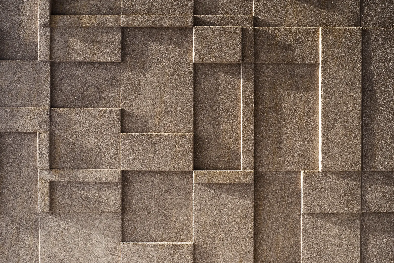 Dettaglio dei pannelli prefabbricati di facciata: moduli rettangolari in rilievo di diverse misure, a grana di pietra bruna