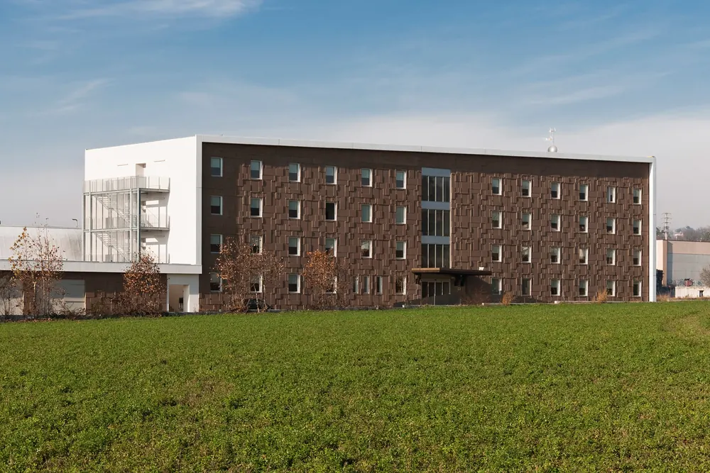 Hotel Dunant visto da lontano, nel campo, con il blocco bianco delle scale