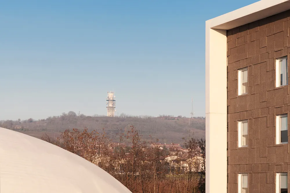 Hotel Dunant: spigolo della facciata a pannelli bruni sul paesaggio della collina