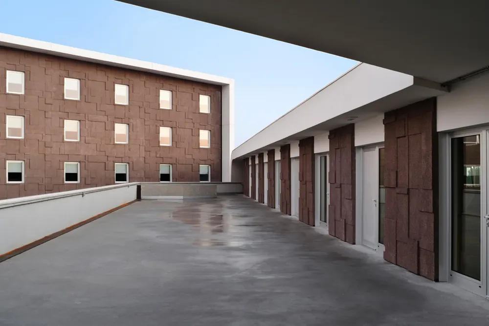 Hotel Dunant: terrazza coperta lungo la facciata a pannelli bruni