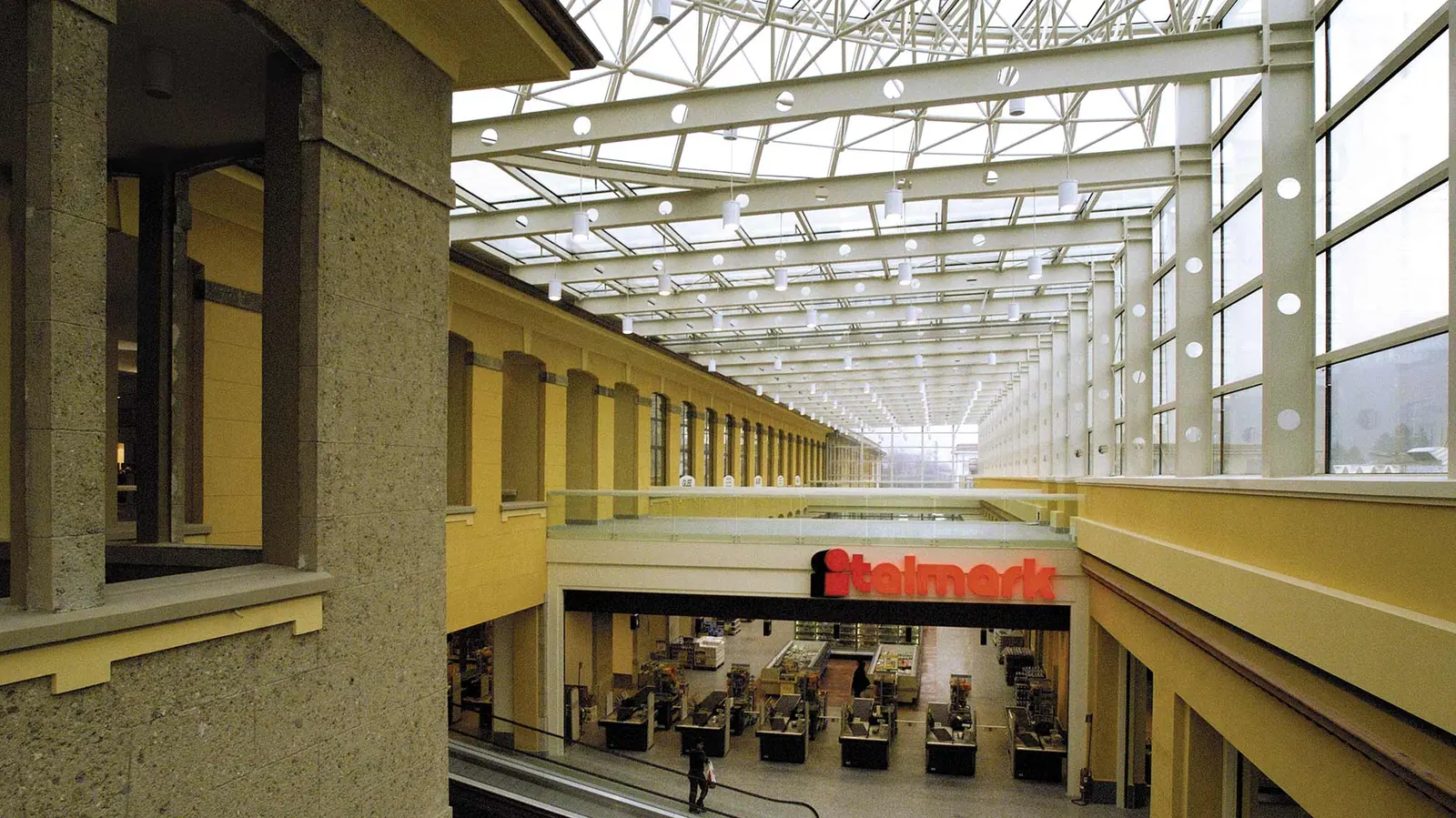 Galleria commerciale Italmark: copertura vetrata su struttura reticolare tra i corpi dell'ex cotonificio, con le facciate color ocra
