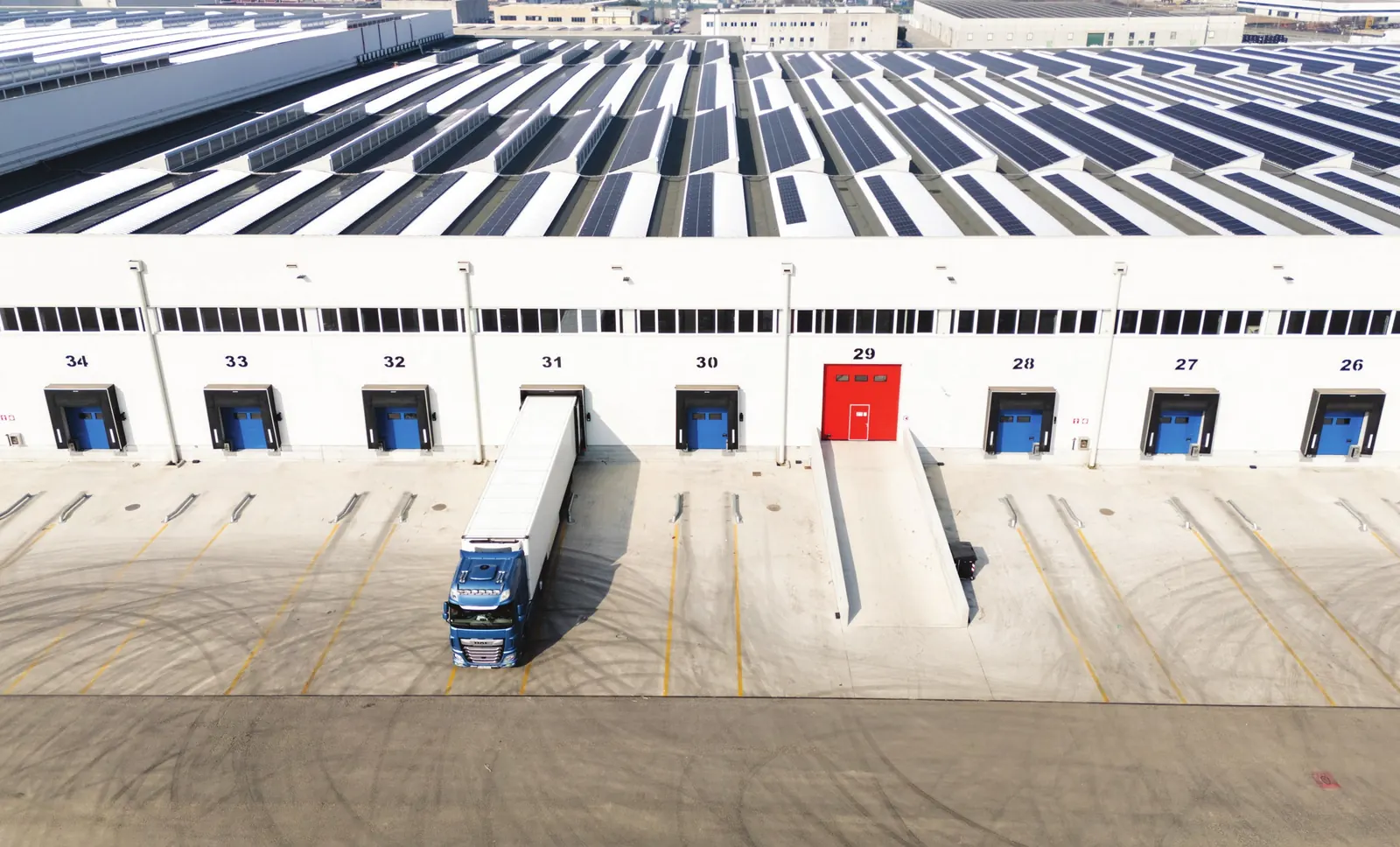 Magazzino Transbozen a Verona visto dall'alto: fronte delle baie di carico con un camion in manovra e copertura fotovoltaica