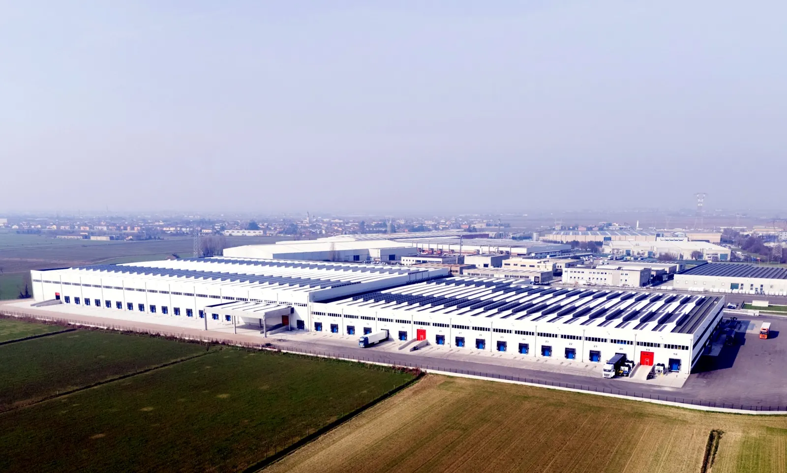 Magazzino Transbozen a Mozzecane visto dall'alto: il lungo edificio bianco con le baie di carico, la copertura fotovoltaica e i campi intorno