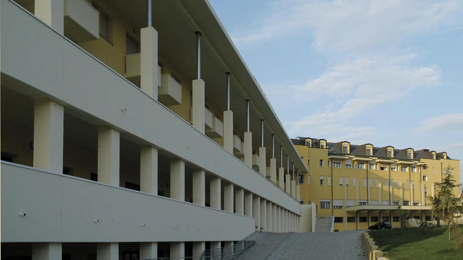 Il portico con colonnato a doppia altezza lungo il nuovo edificio, visto di scorcio verso la sede esistente